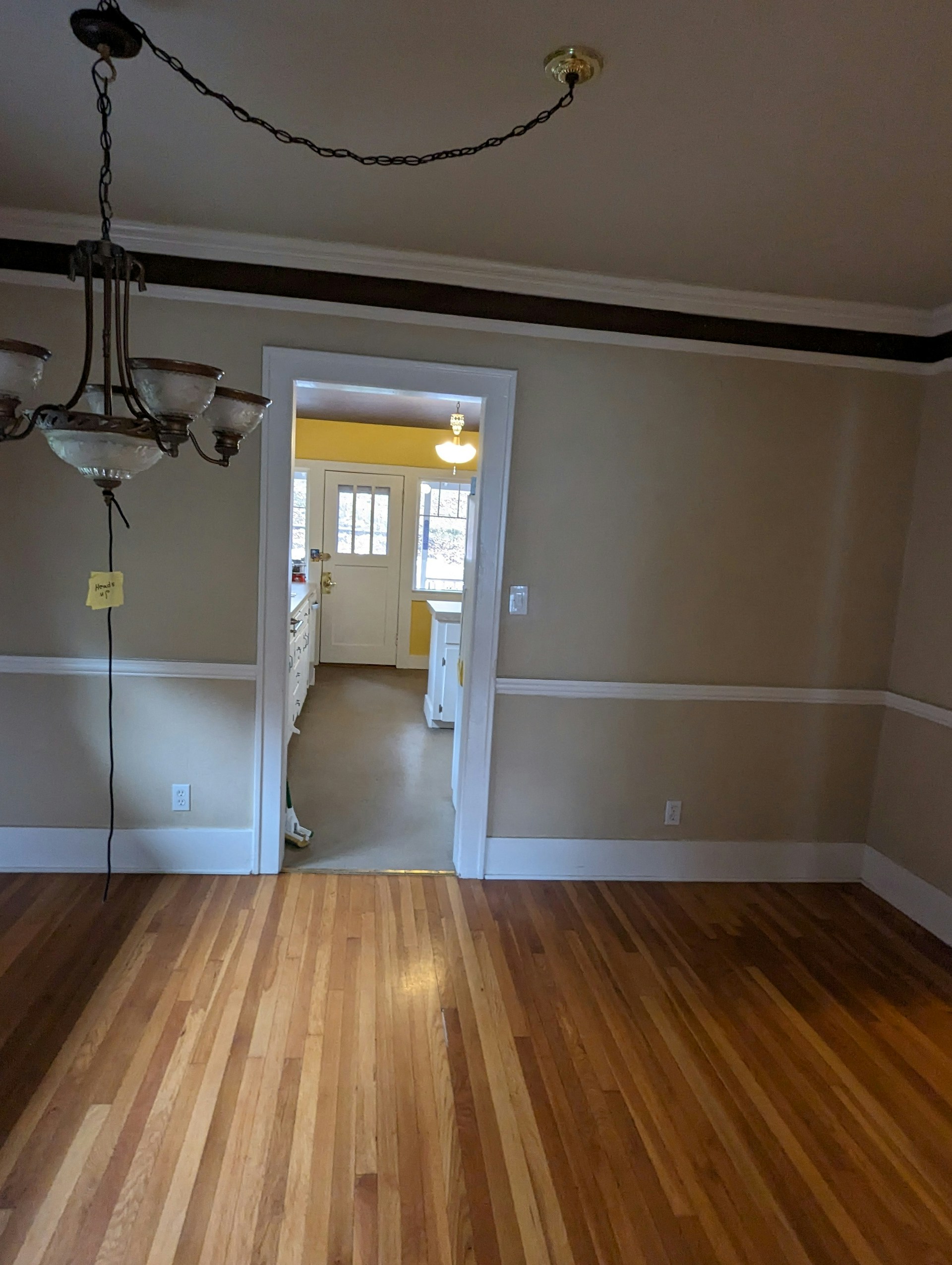 an empty room with hard wood floors and a chandelier