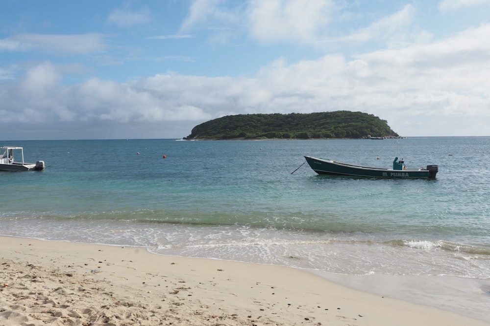 um barco na praia com uma pequena ilha ao fundo