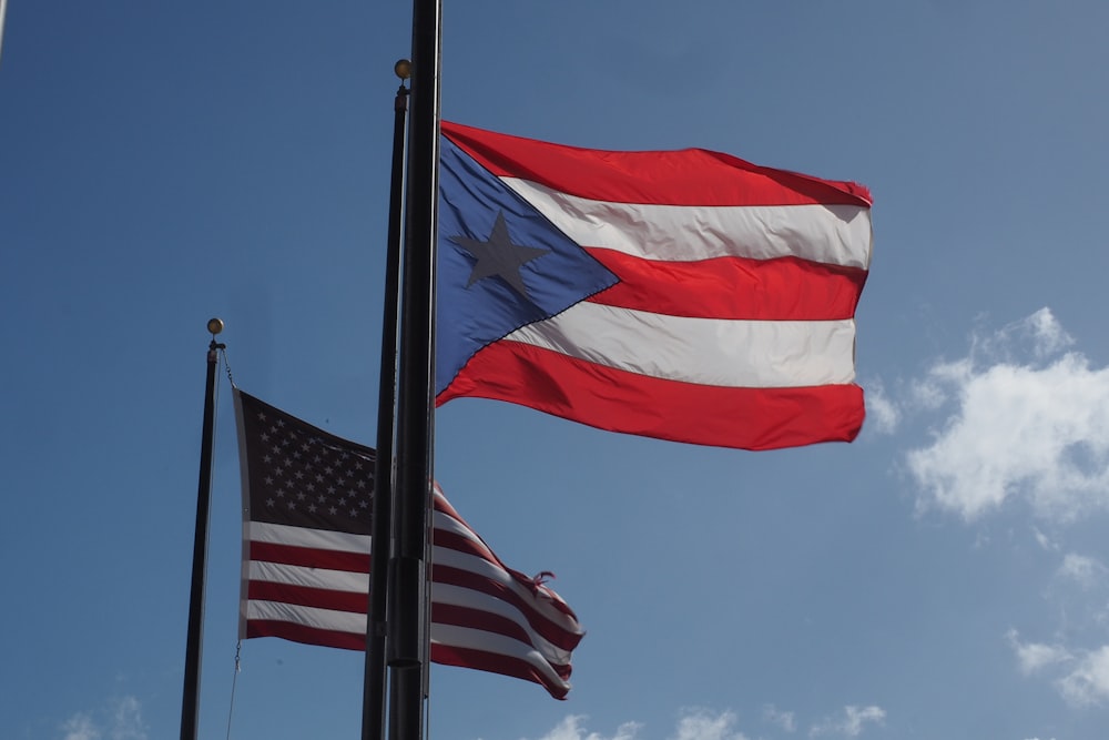 two flags flying next to each other under a blue sky