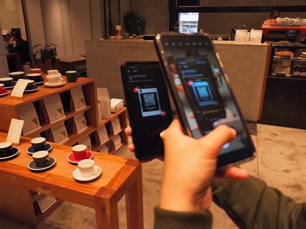 a person holding up a smart phone in front of a counter