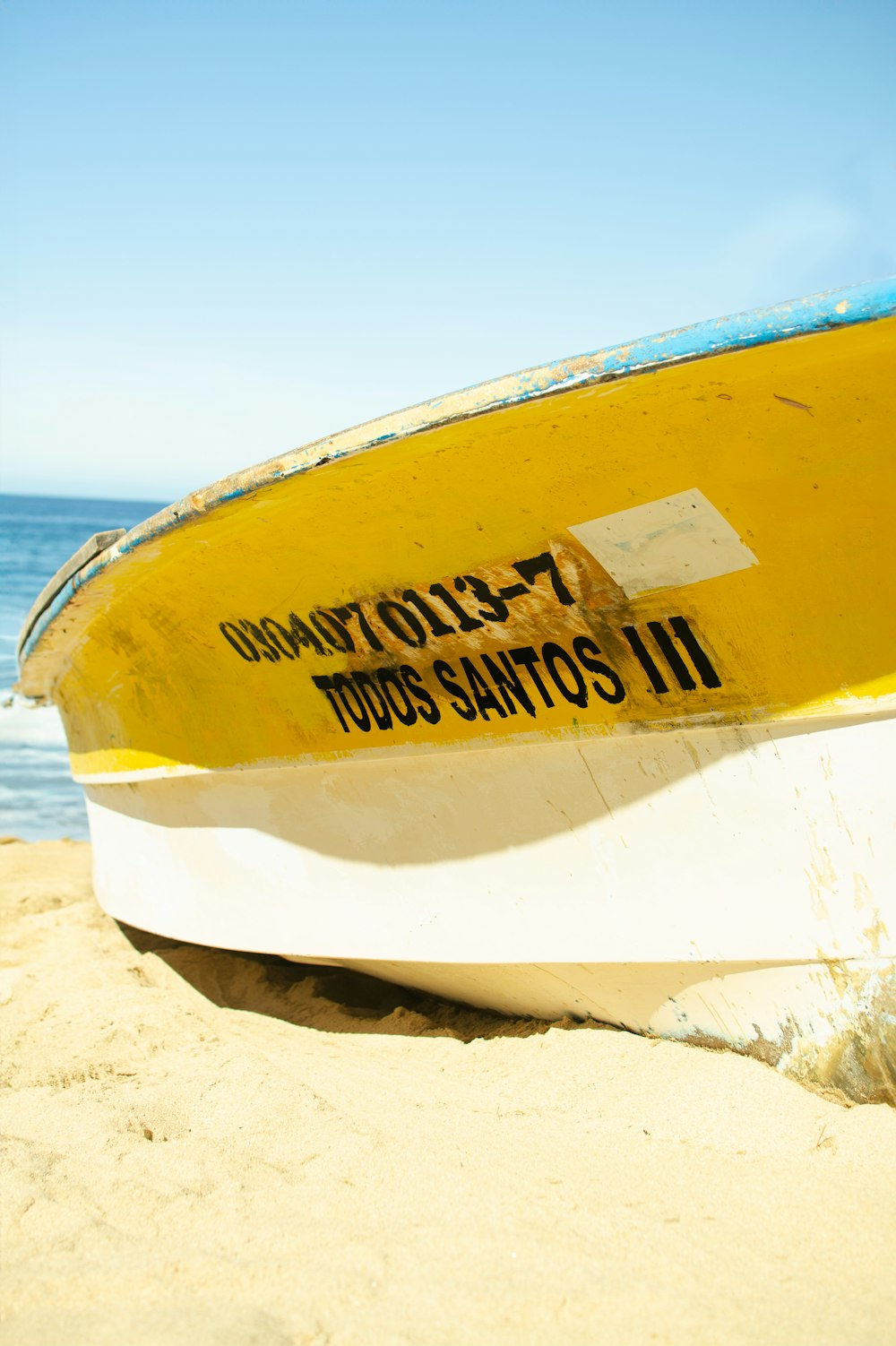 a yellow and white boat sitting on top of a sandy beach