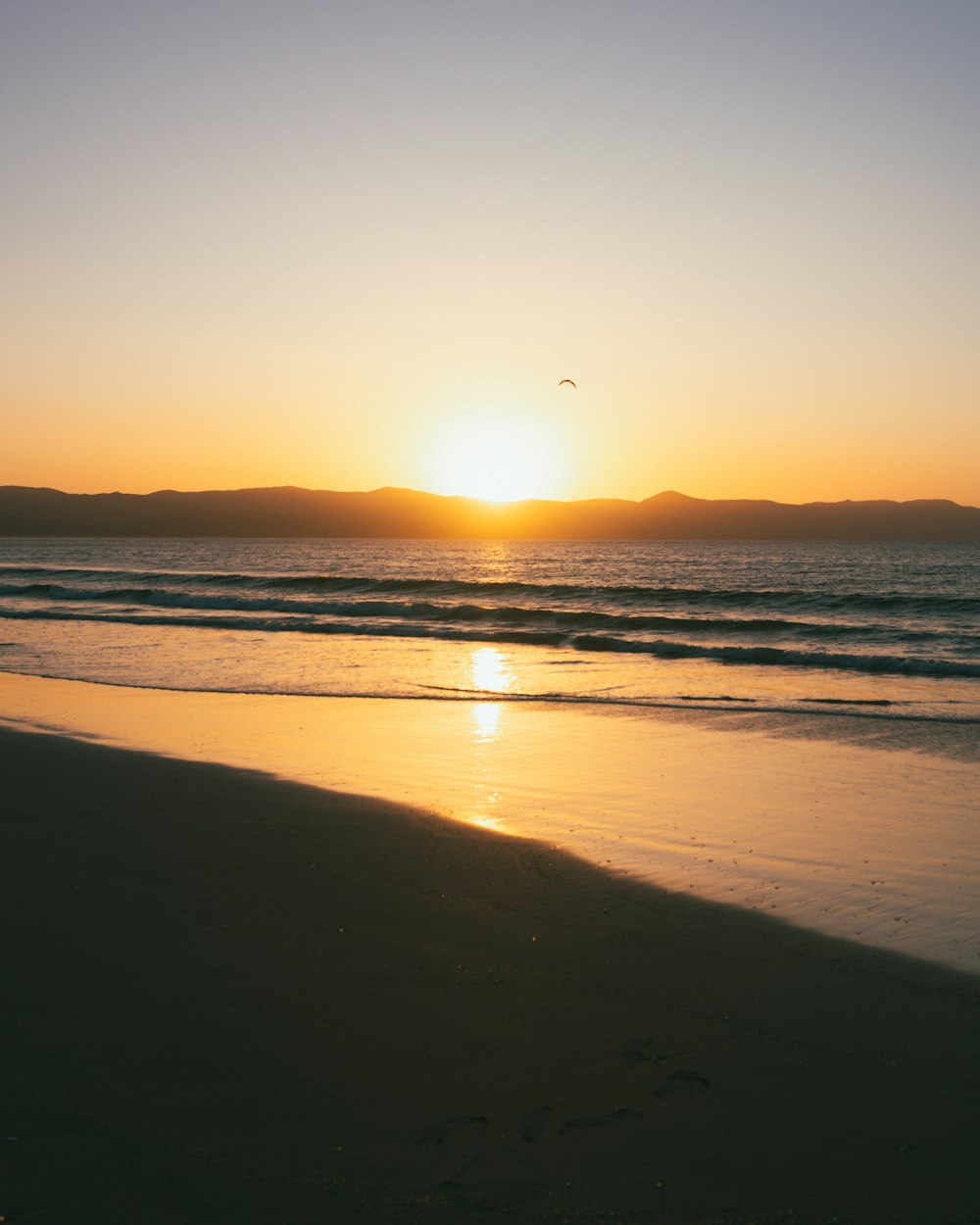 the sun is setting over the ocean on the beach