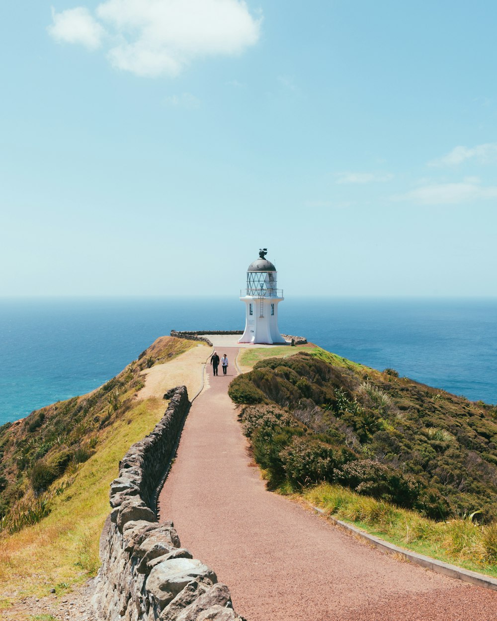 a lighthouse on top of a hill next to the ocean