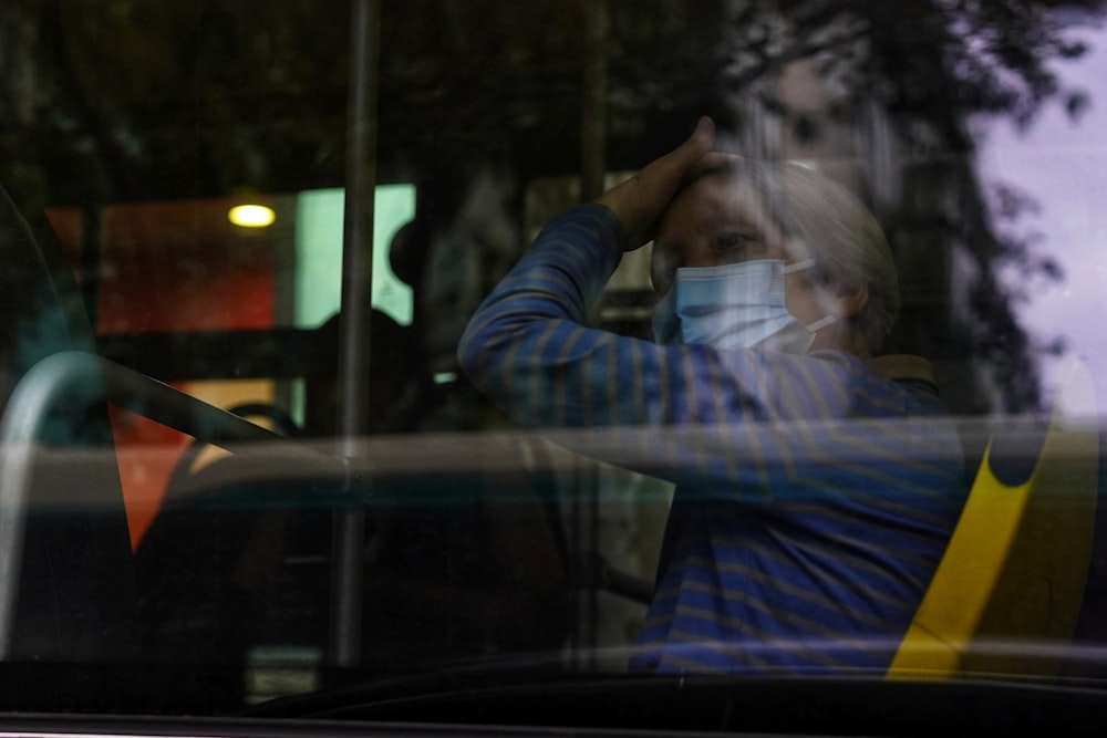 a woman wearing a face mask is seen through a window