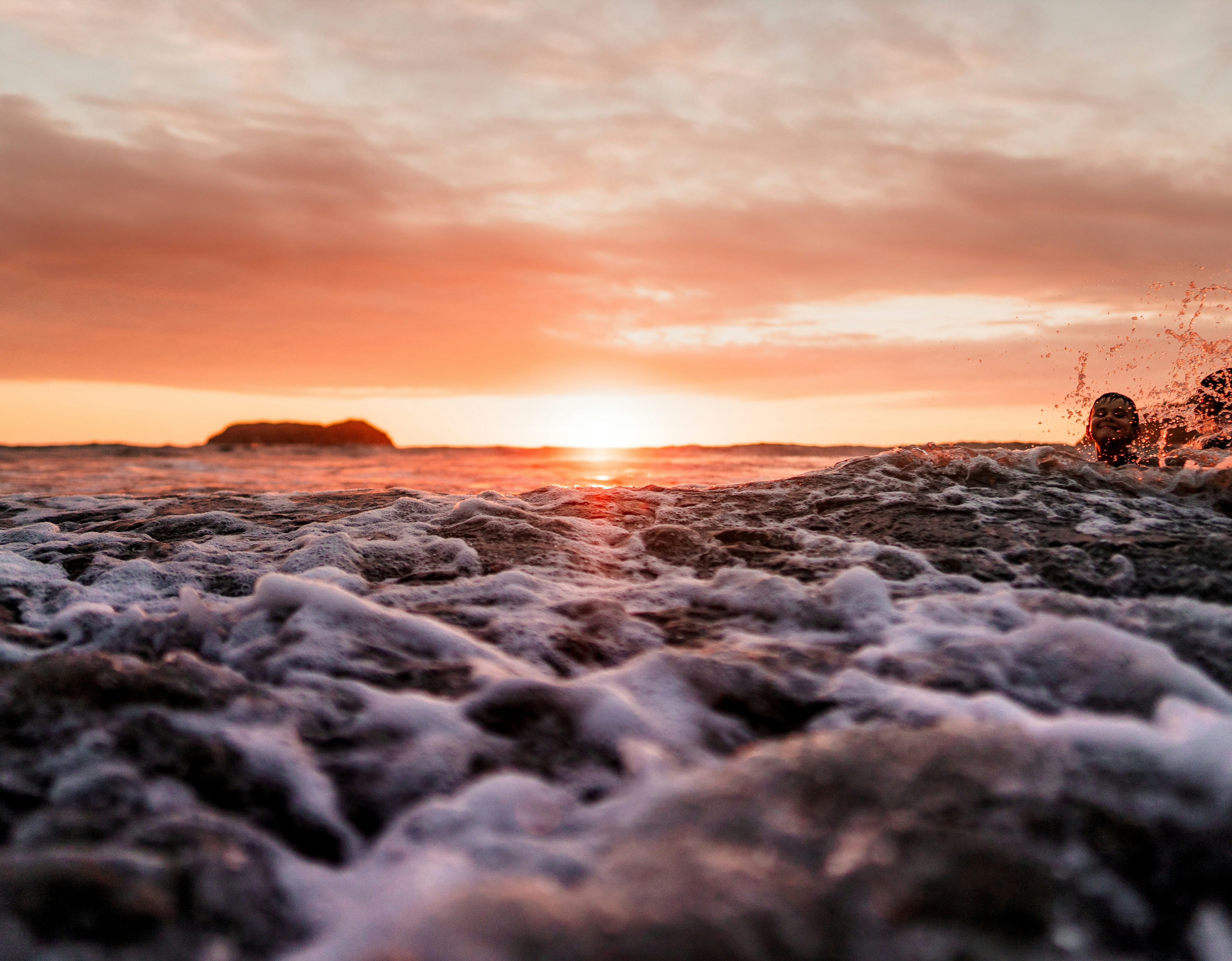 the sun is setting over the ocean with foamy waves