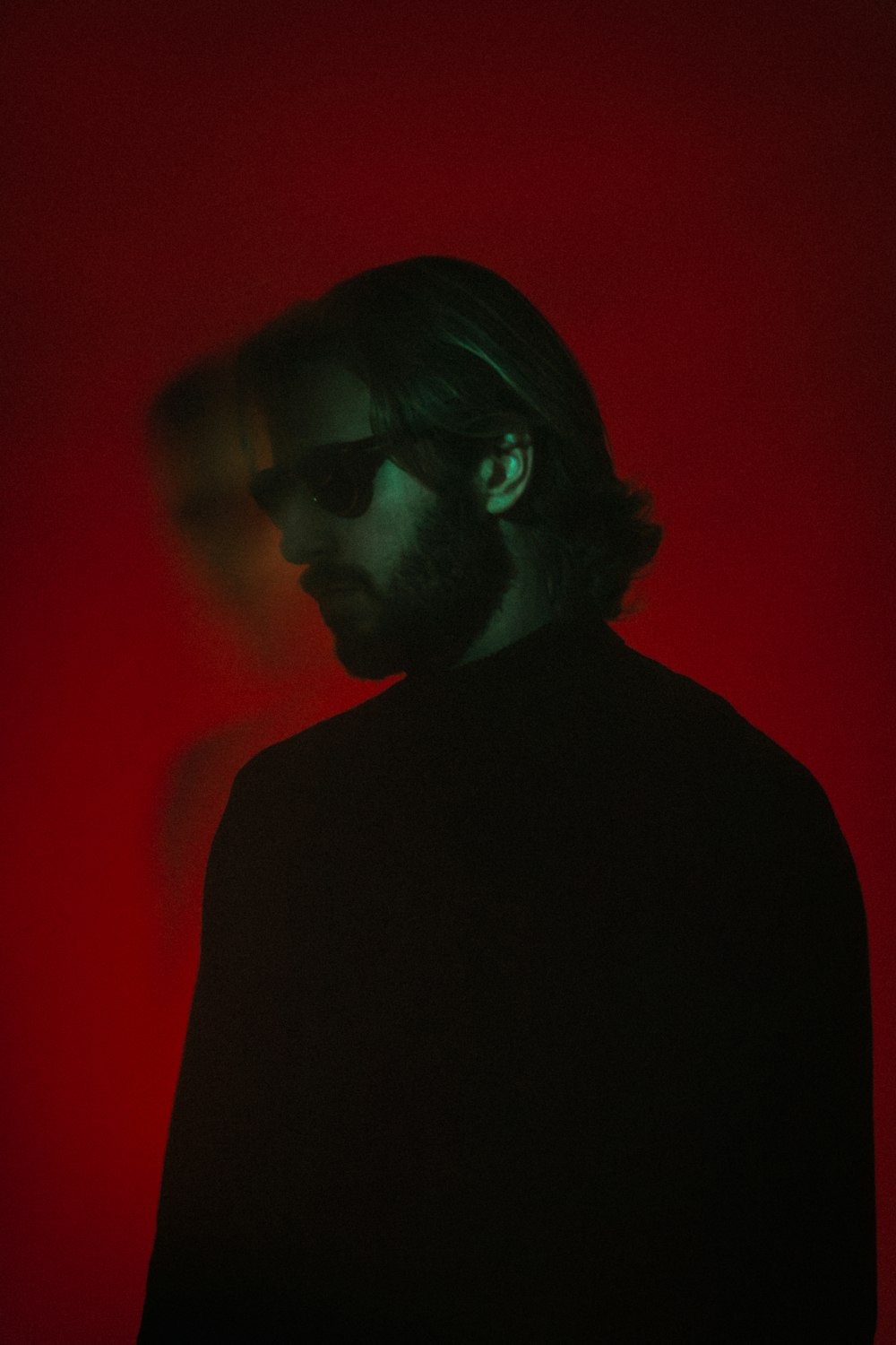 a man with long hair and glasses in a dark room