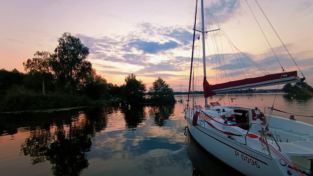 a sailboat sitting in the water at sunset