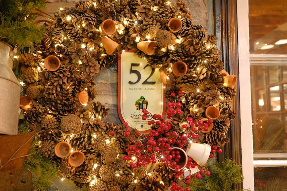 a wreath with pine cones and bells on a window sill