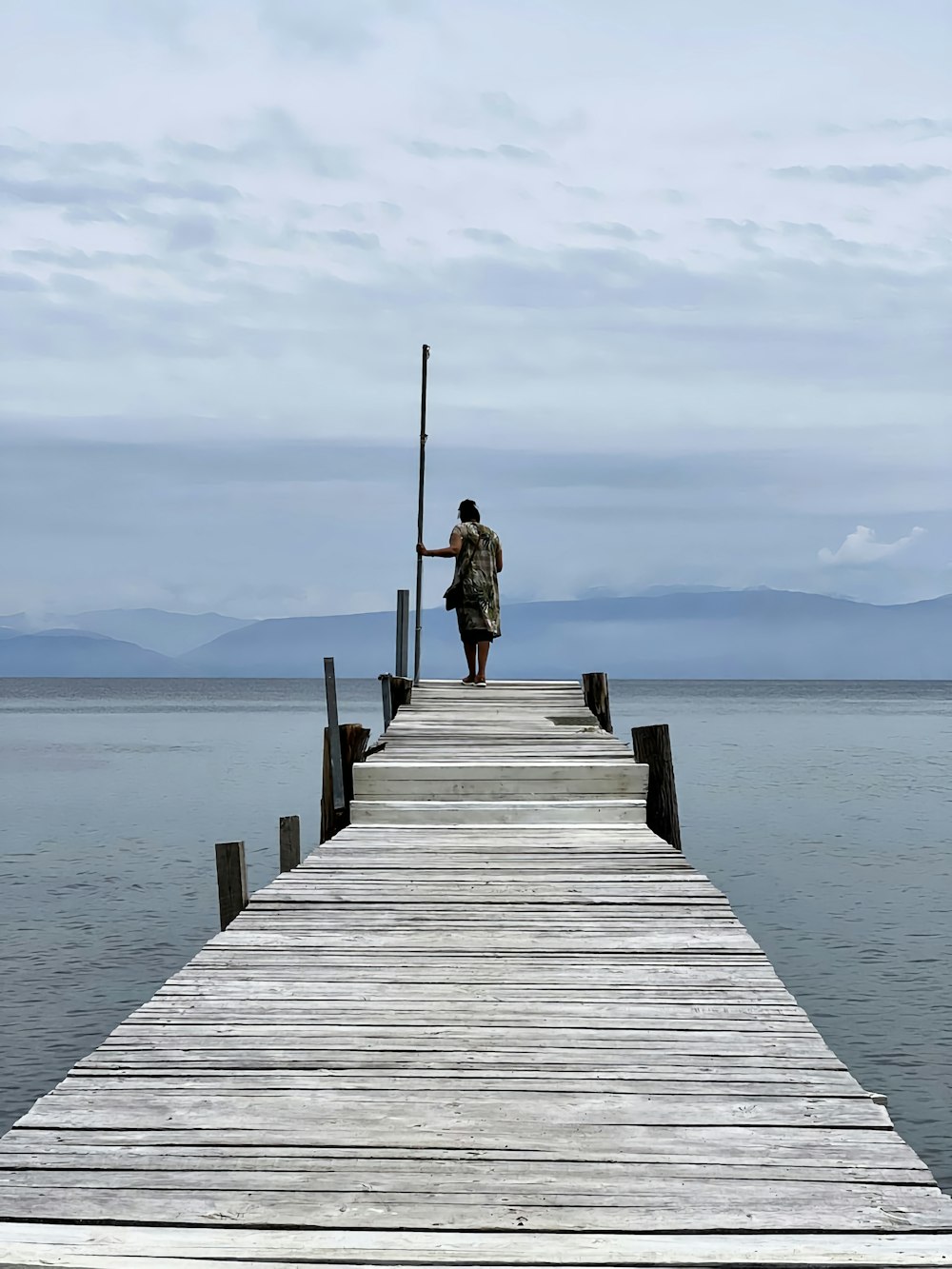 a man standing on a pier looking out at the water