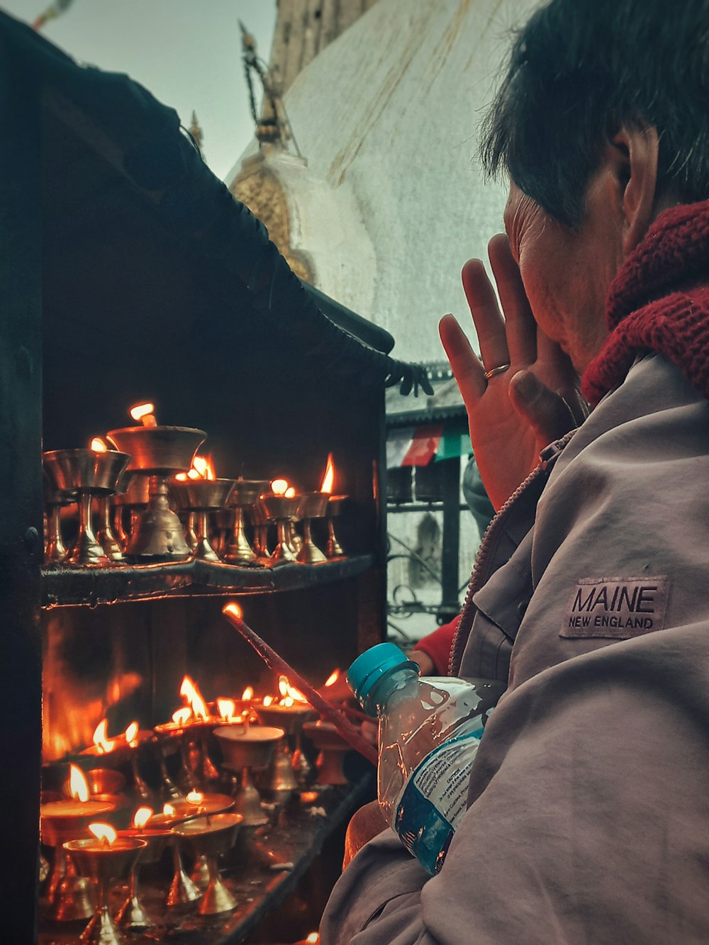 a man holding a bottle of water in front of a fire