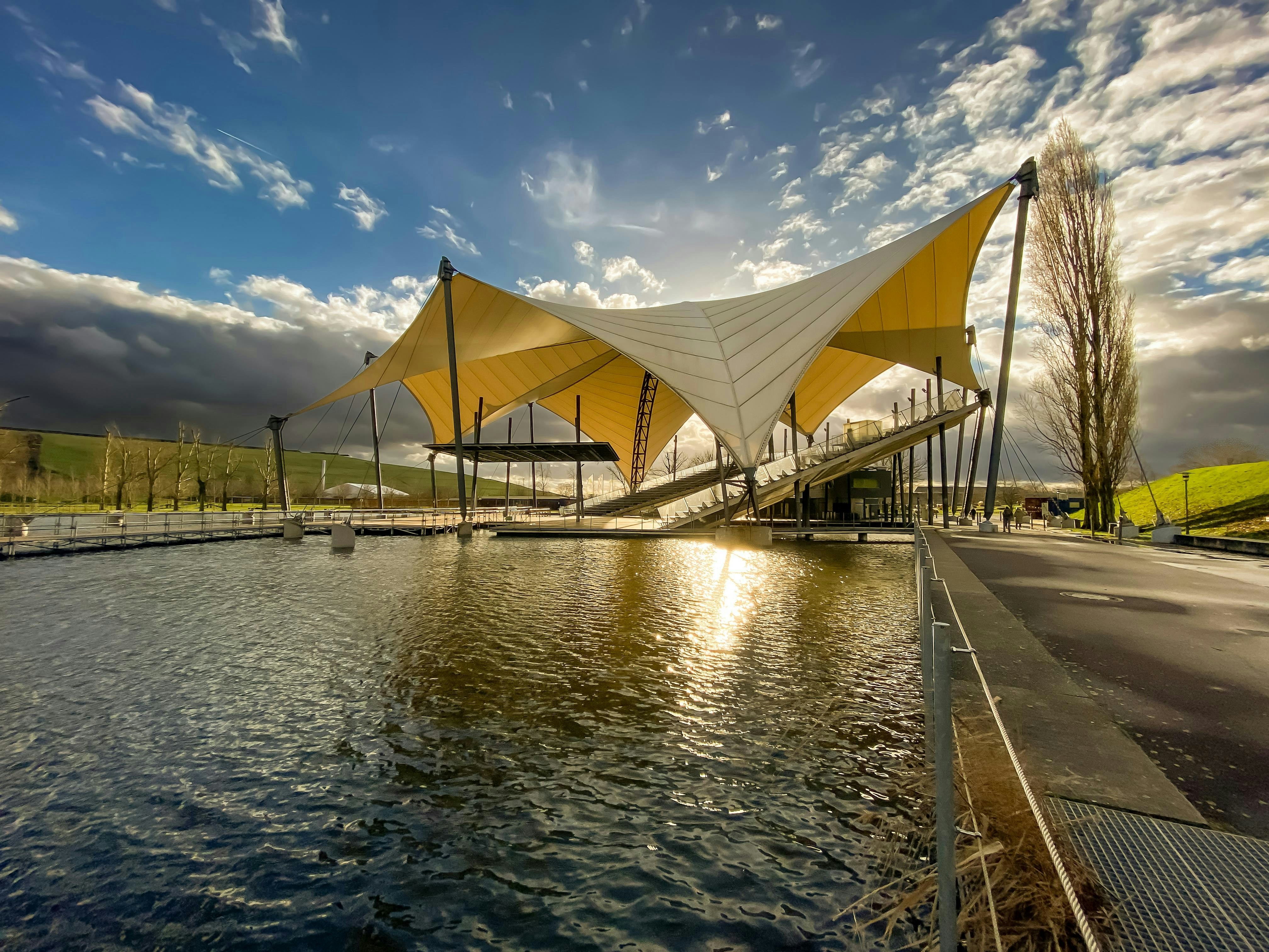 A large building sitting next to a body of water photo – Free Sunset ...