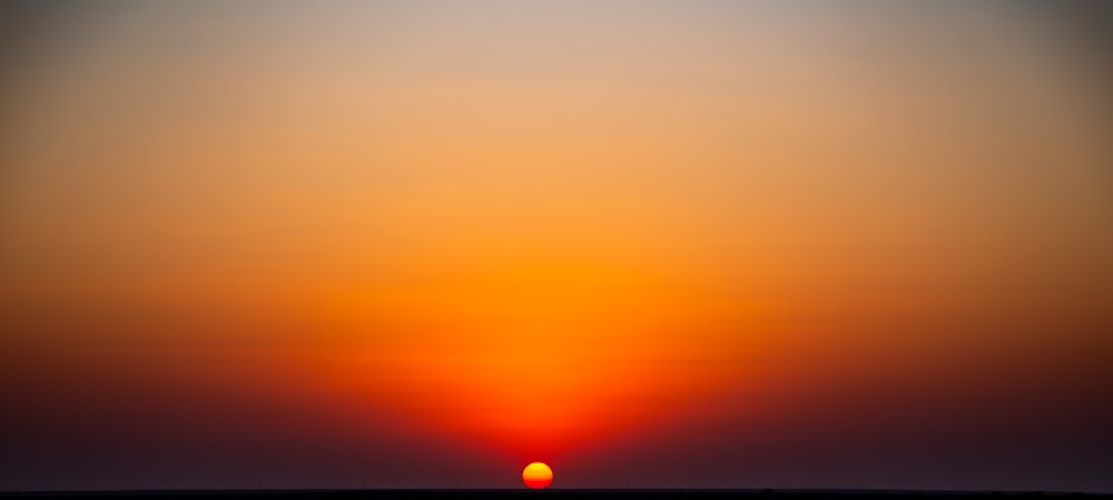 the sun is setting over the horizon of a body of water