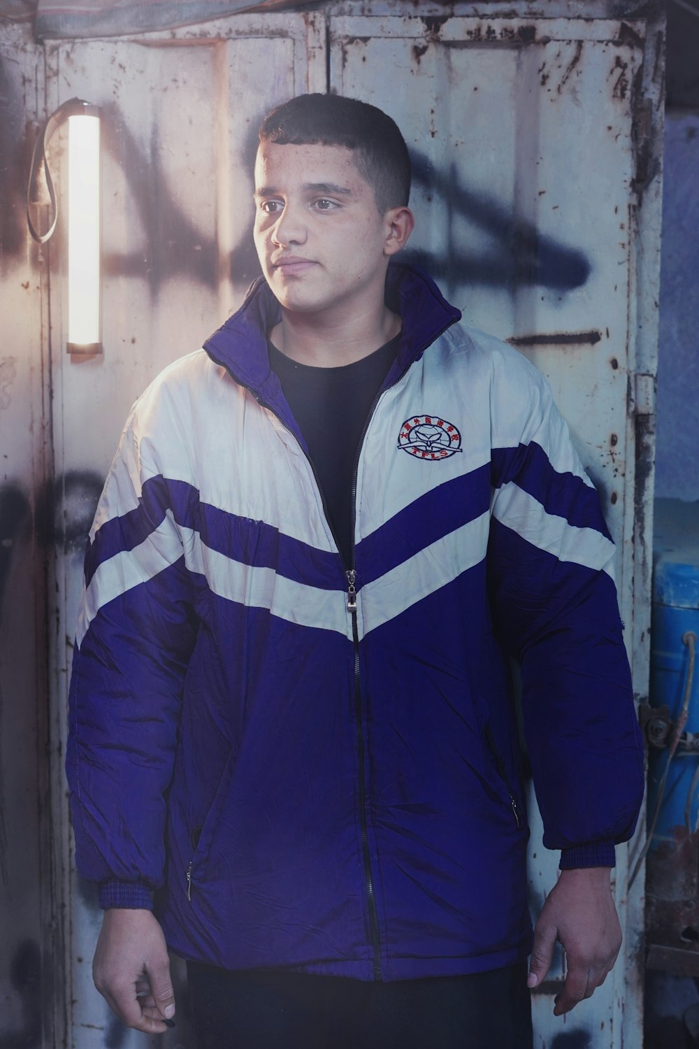 a man in a blue and white jacket standing in front of a door