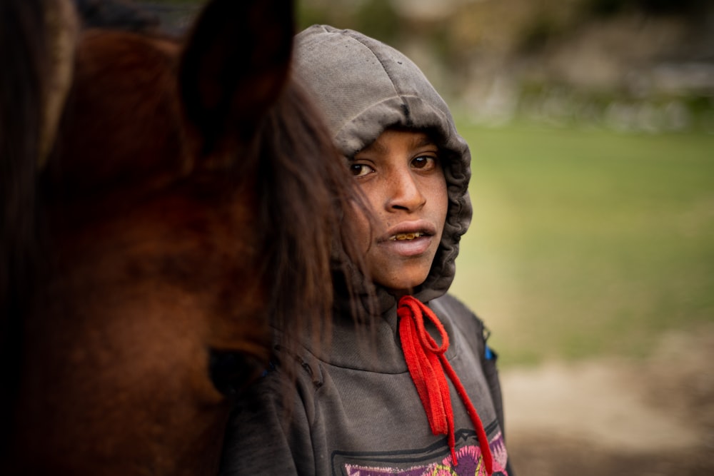 a young boy standing next to a brown horse