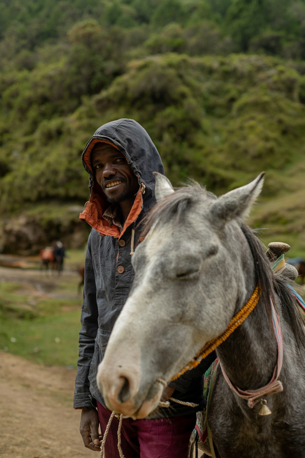 a man standing next to a horse on a dirt road