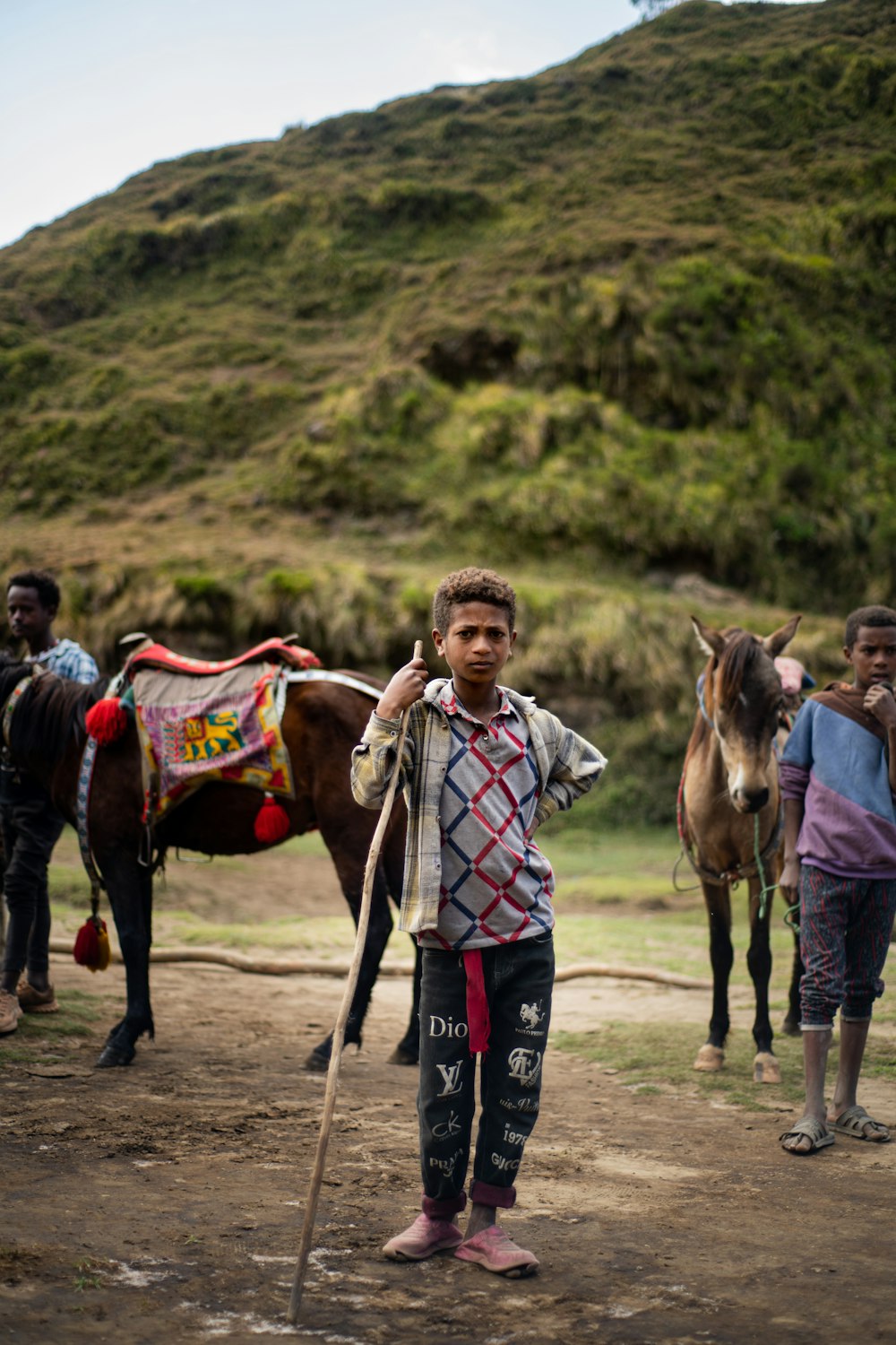 a young boy standing next to a horse on a dirt road