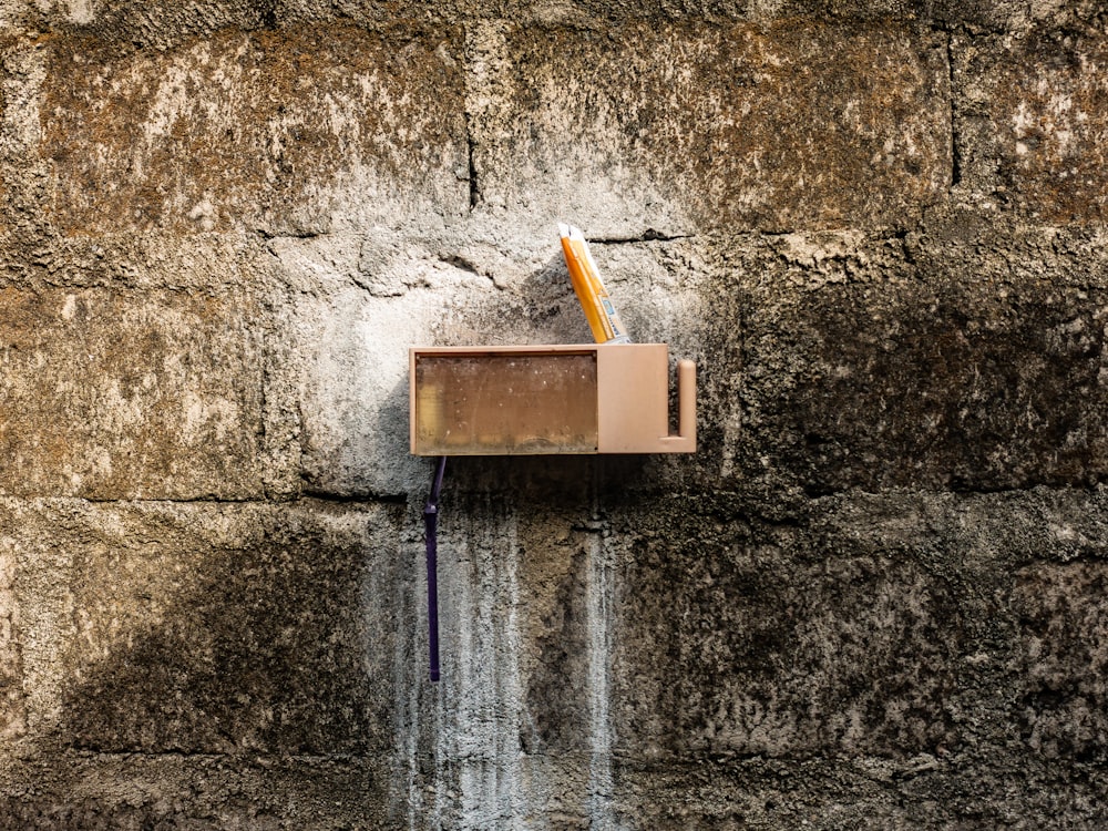 a brick wall with a pen and pencil holder attached to it