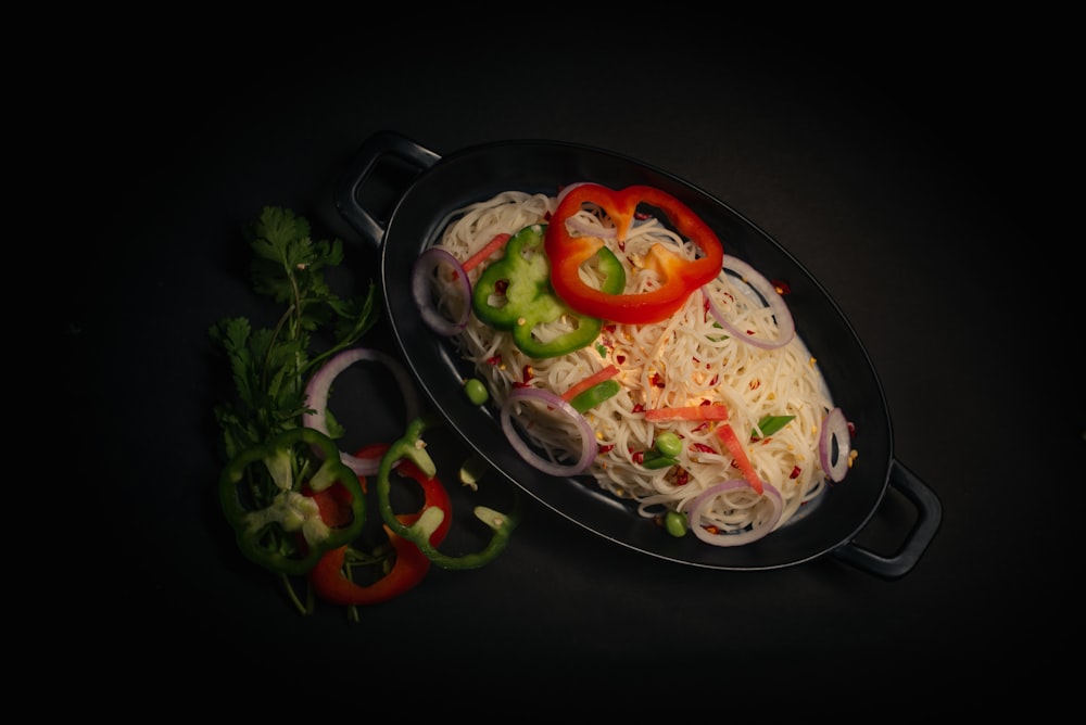 a pan filled with noodles and vegetables on top of a table