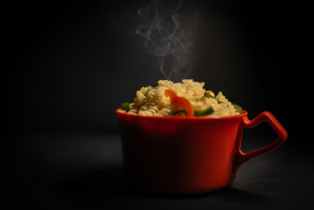 a red bowl of food with steam rising out of it