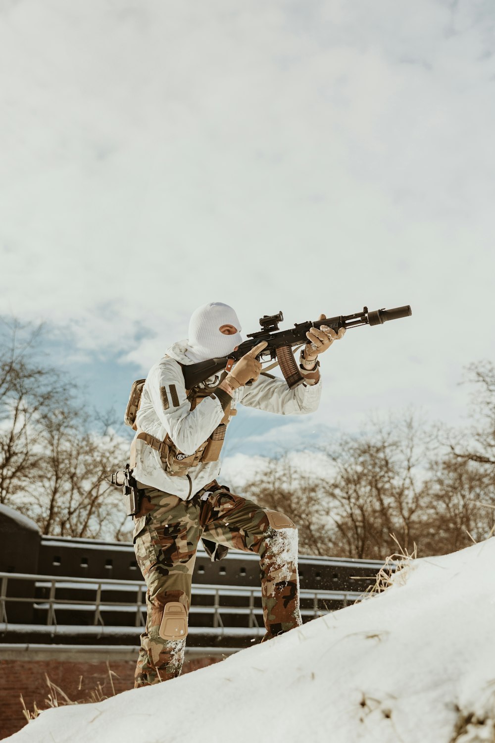 a man holding a rifle while standing on top of a snow covered hill