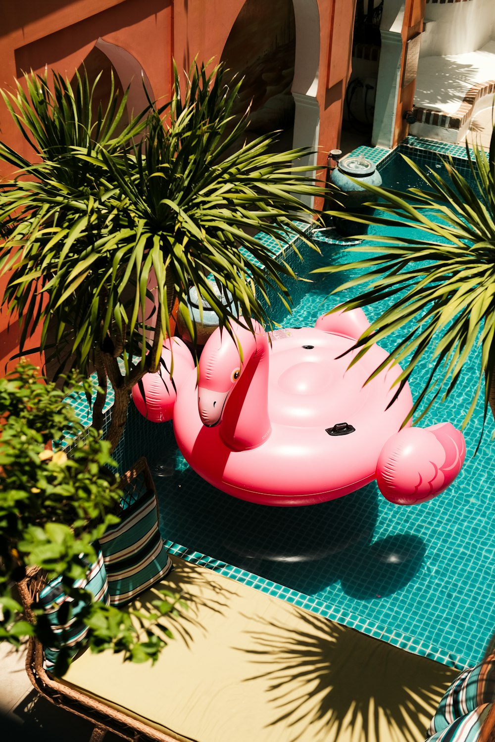 a pink inflatable pig sitting next to a potted plant