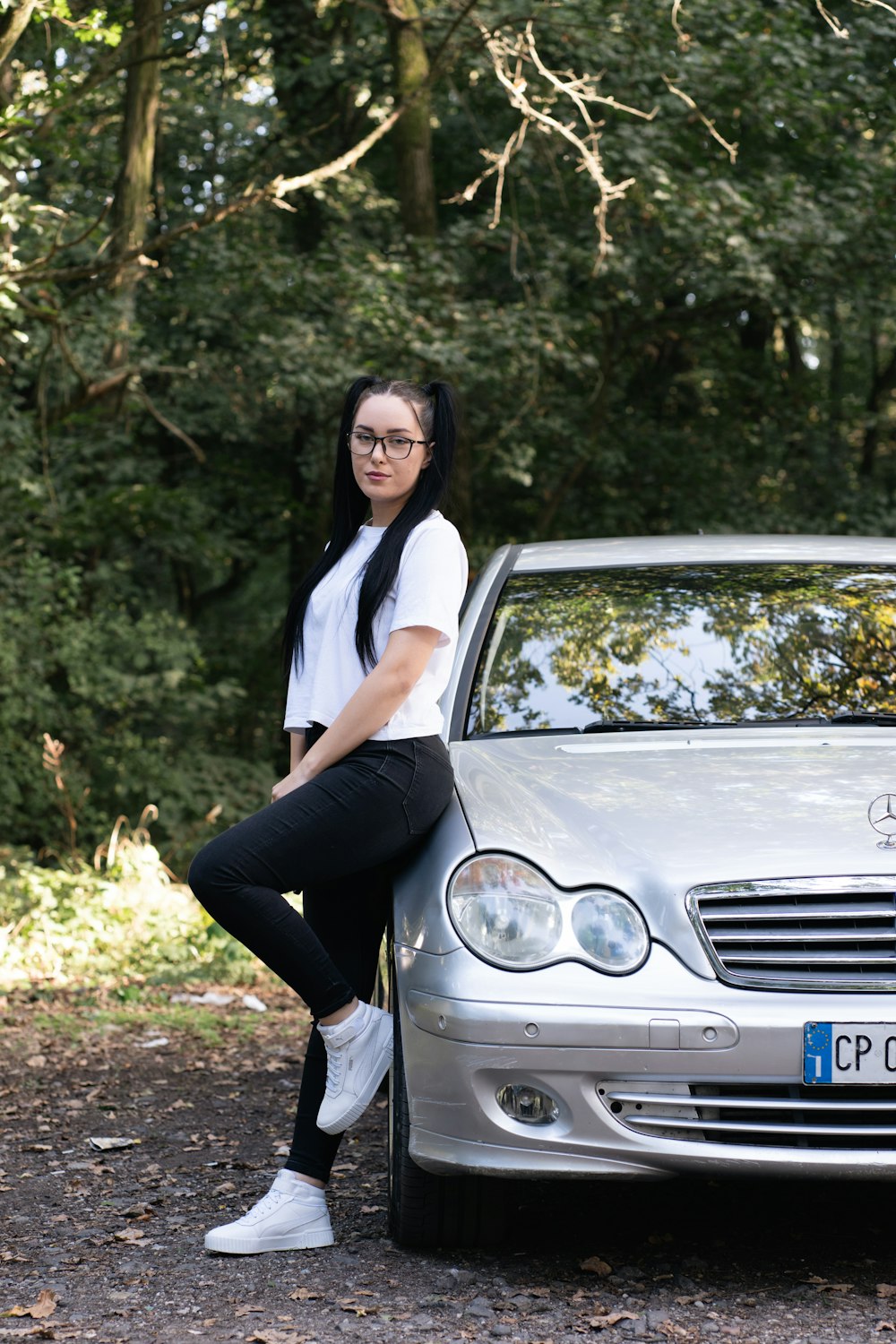 a woman sitting on the hood of a silver car