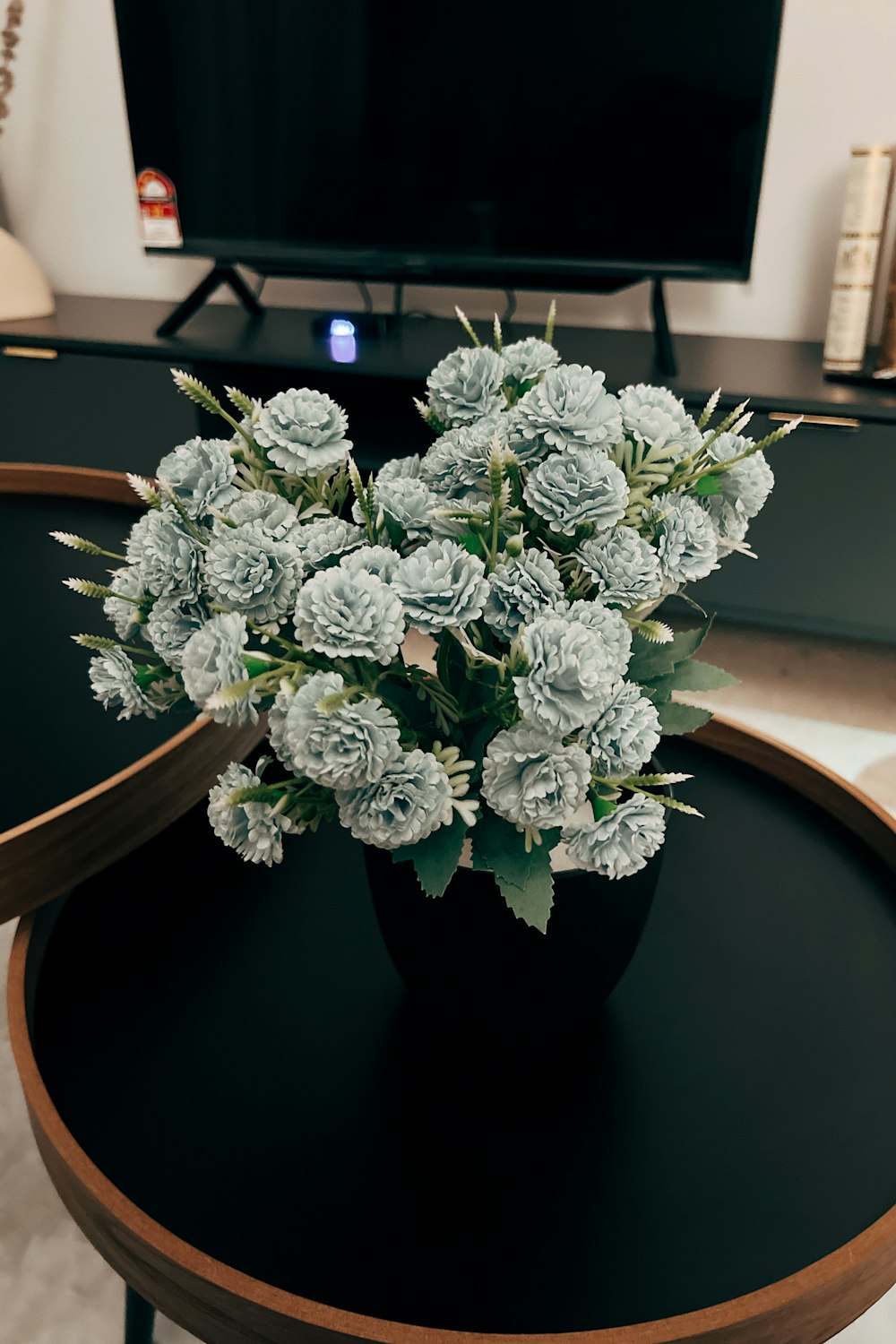a vase of flowers sitting on a table in front of a tv