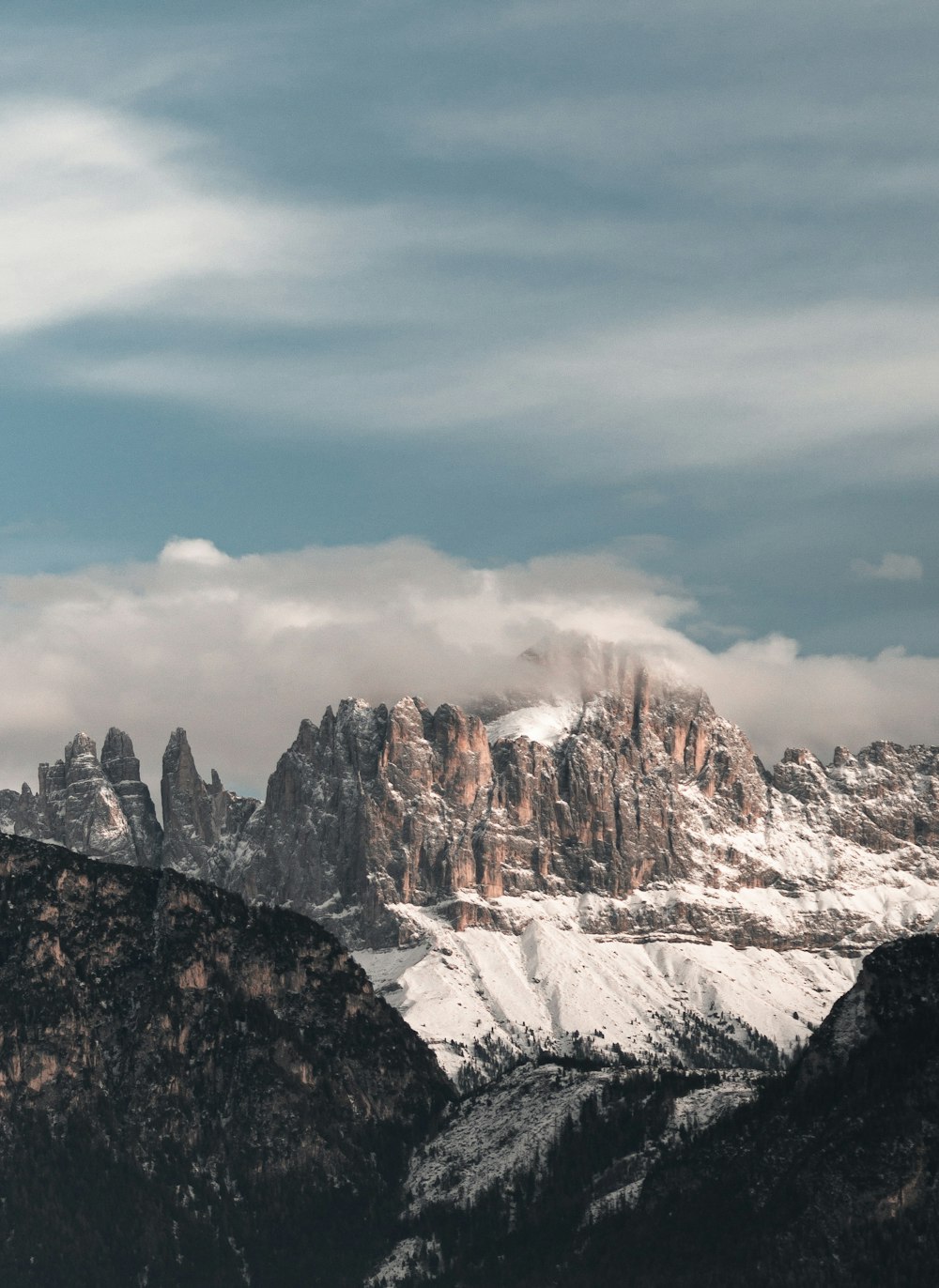 a group of mountains covered in snow under a cloudy sky