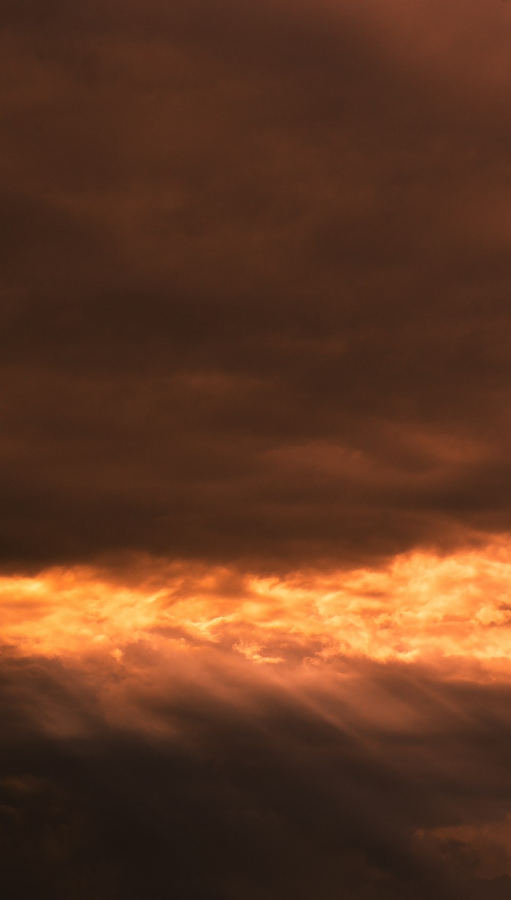 a plane flying through a cloudy sky at sunset