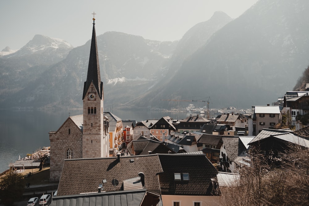 a view of a town with a church steeple and mountains in the background