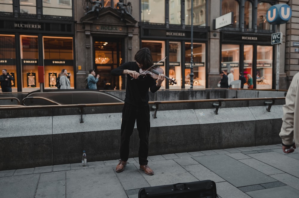 a person standing on a sidewalk playing a violin