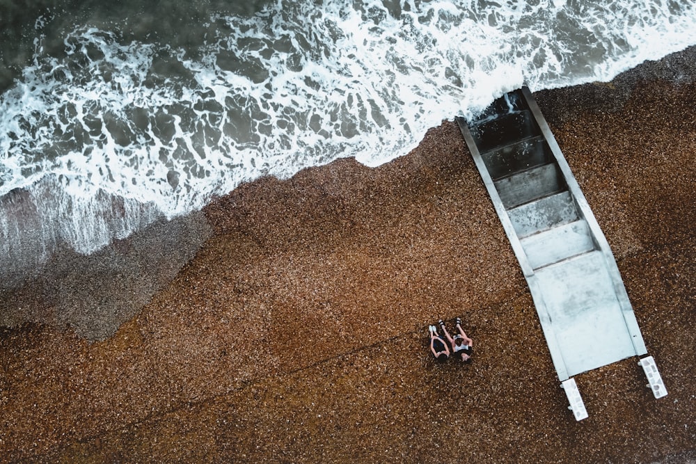 a couple of people laying on top of a beach next to the ocean