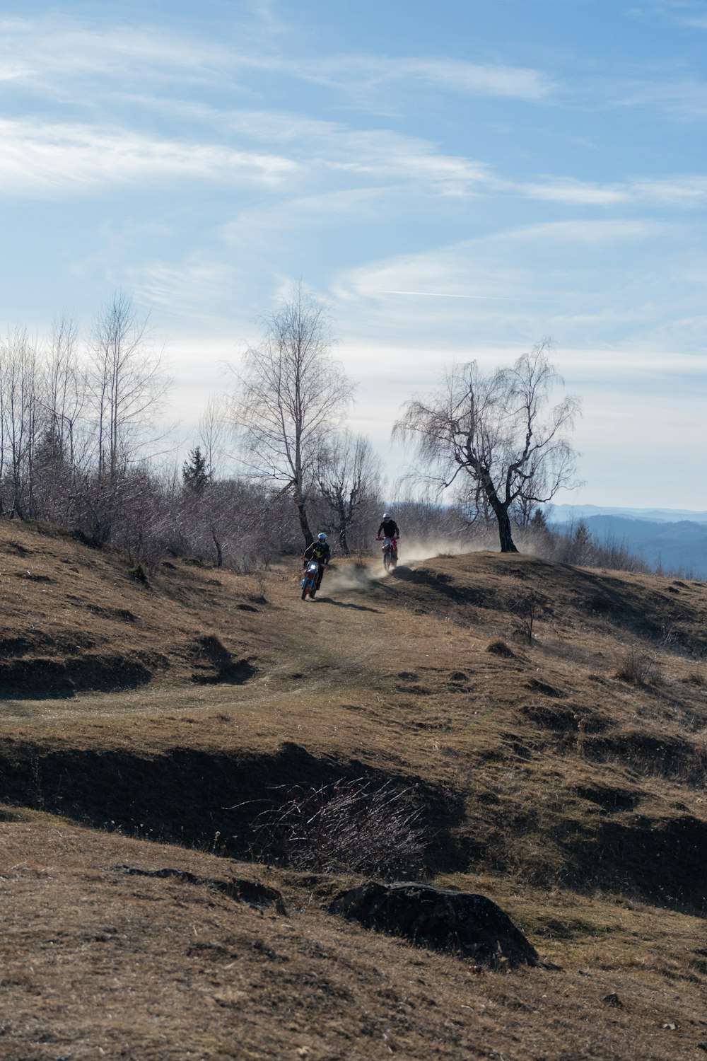 a couple of people riding bikes down a dirt road