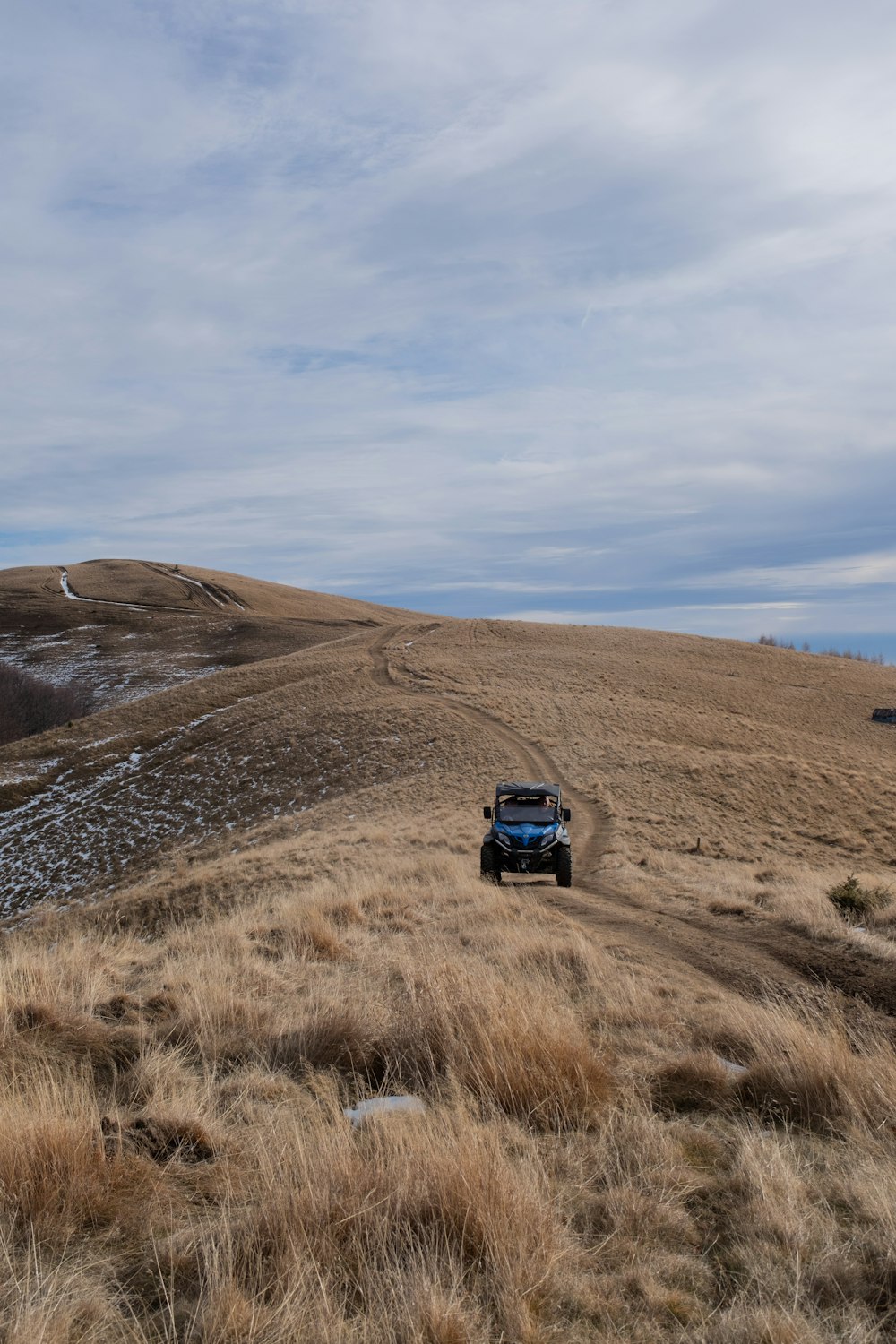 a truck driving down a dirt road in the middle of a field