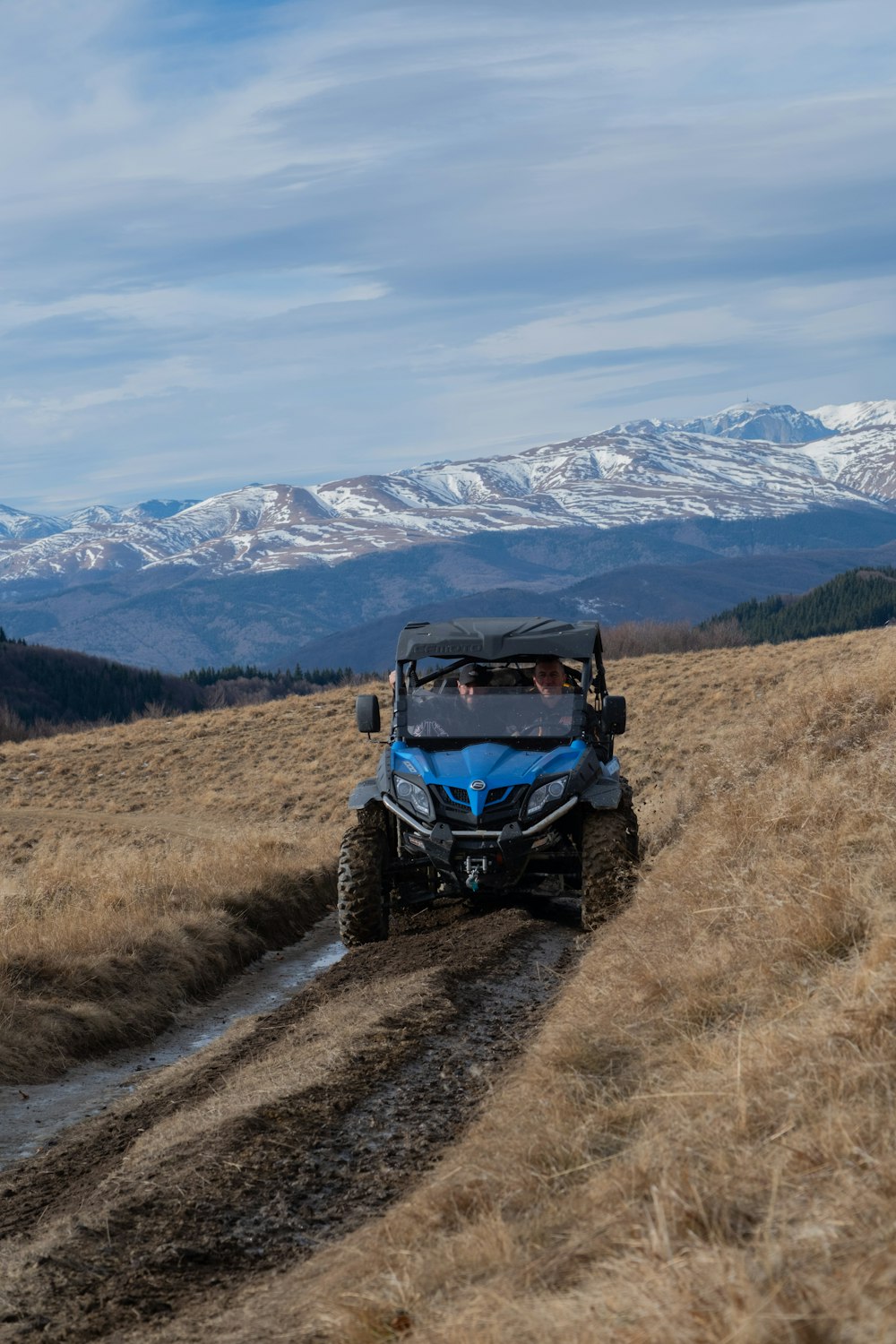 a blue four - wheeler driving down a dirt road