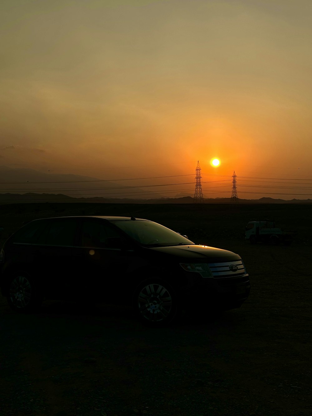 a car parked in a field with the sun setting in the background