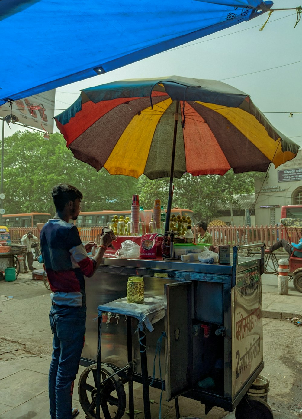 a person standing under an umbrella near a food cart