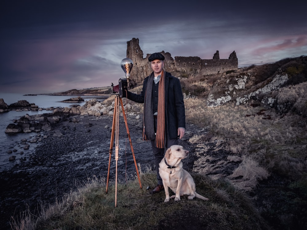 a man standing next to a dog holding a camera