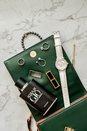 a green purse with a watch and other items