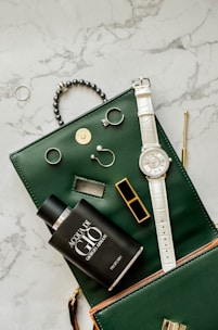 a green purse with a watch and other items