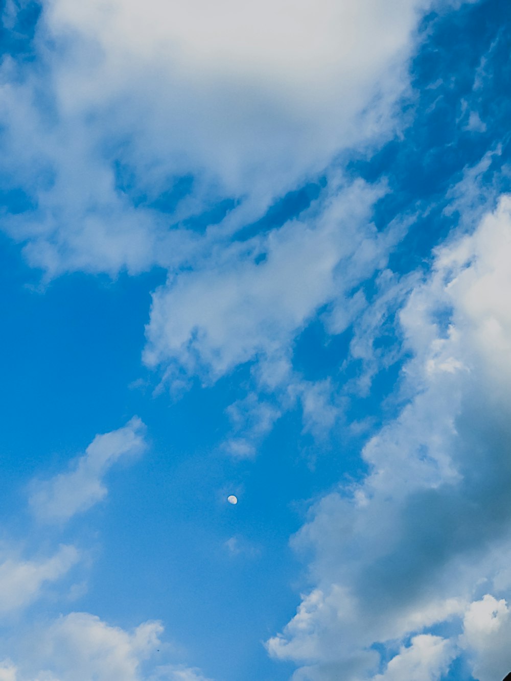 a blue sky with clouds and a half moon