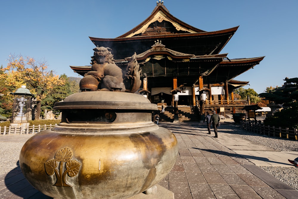 a large golden vase sitting in front of a tall building