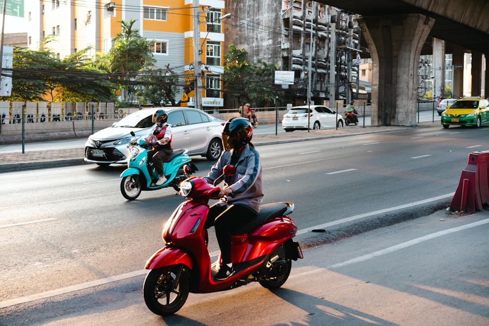 a couple of people riding on the back of a red scooter