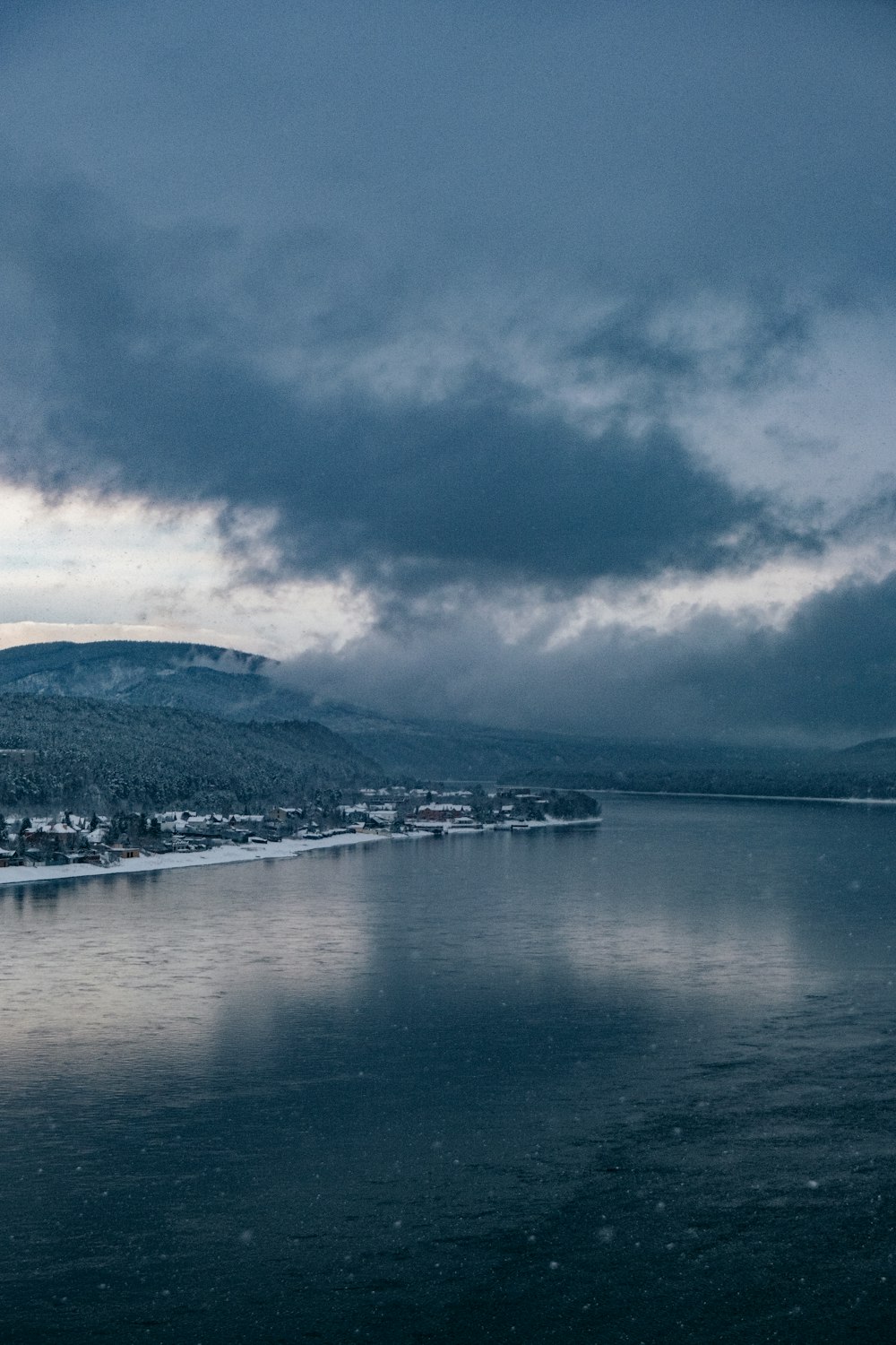 a body of water surrounded by mountains under a cloudy sky