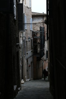 a narrow alley way with a clock tower in the distance