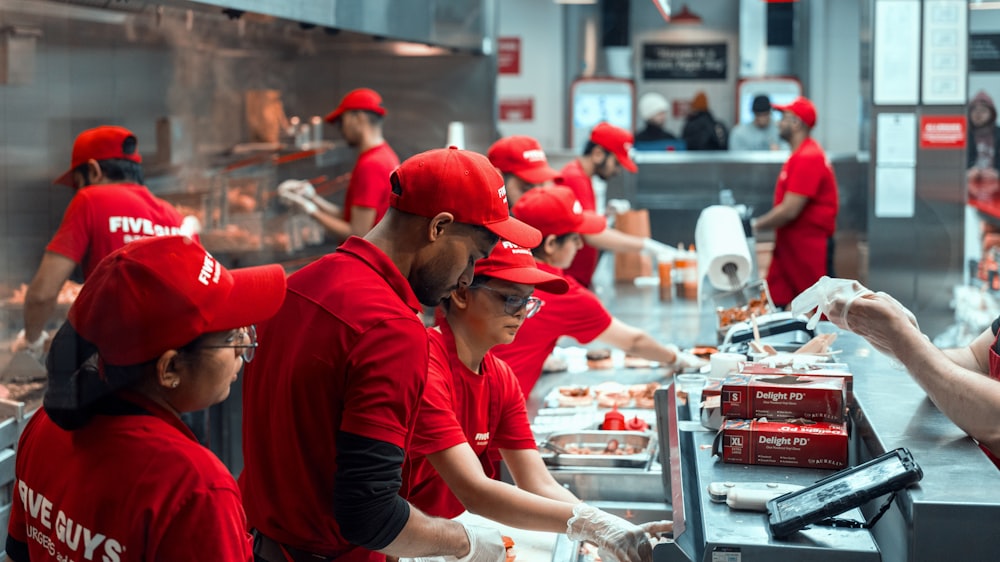 a group of people in red uniforms preparing food