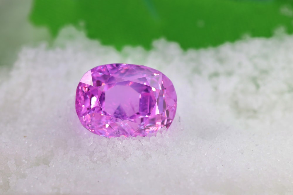 a pink diamond sitting on top of a pile of snow
