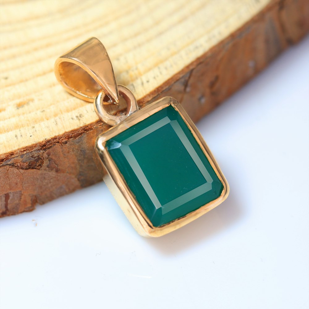 a gold pendant with a green stone on it