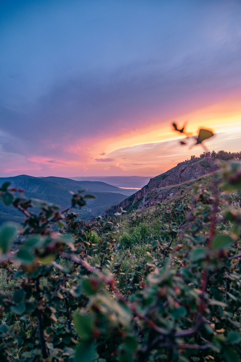 Die Sonne geht über den Bergen und Bäumen unter