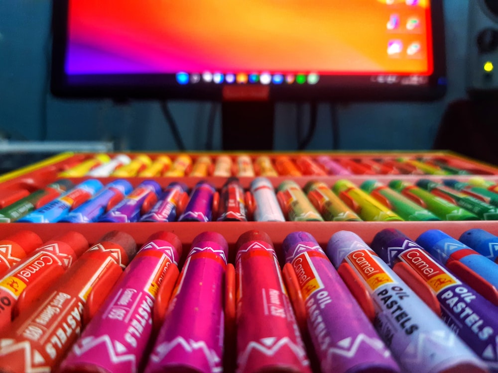 a bunch of crayons are lined up in front of a computer screen